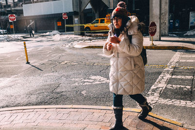 Woman standing on road in city