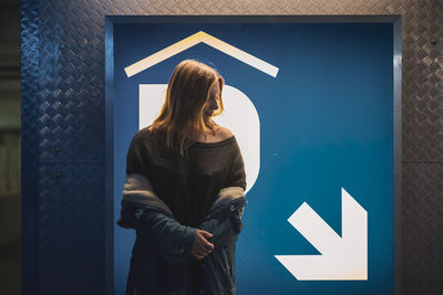 Woman standing against information sign