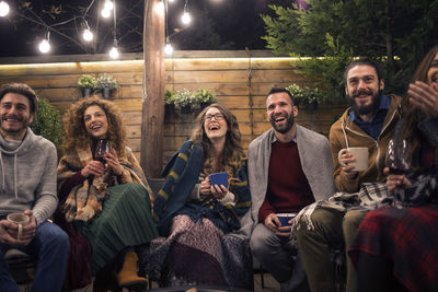 Cheerful friends with drinks in backyard at night