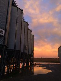 Low angle view of cropped silos against clouds