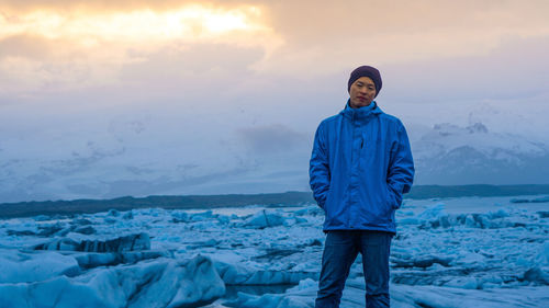 Portrait of man standing by frozen sea during winter