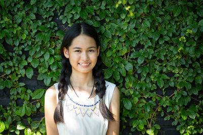 Portrait of smiling girl standing against plants