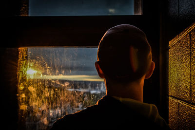 Close-up of boy looking through window