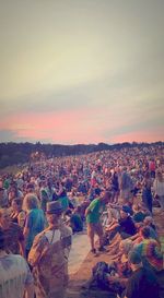 Crowd at town against sky during sunset