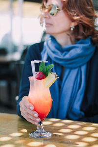 Midsection of woman holding drink on table