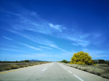 Road passing through landscape against blue sky