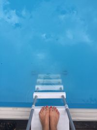 Low section of woman on ladder at poolside