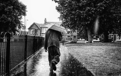 Rear view of woman walking on wet street in rain