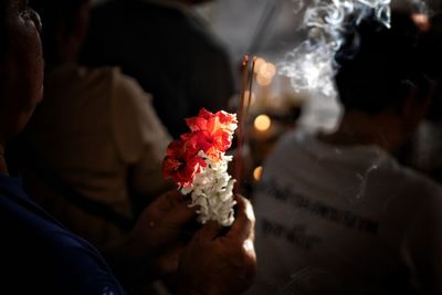 Close-up of person holding flowers and incense at temple