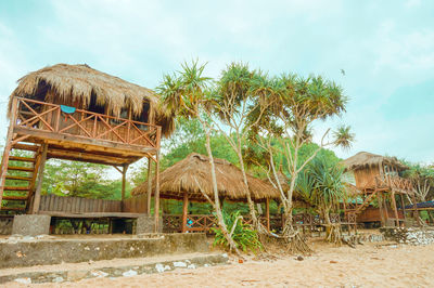 Built structure and trees by house against sky