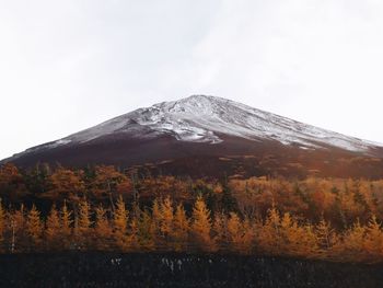 Scenic view of mountain and trees in autumn against cloudy sky