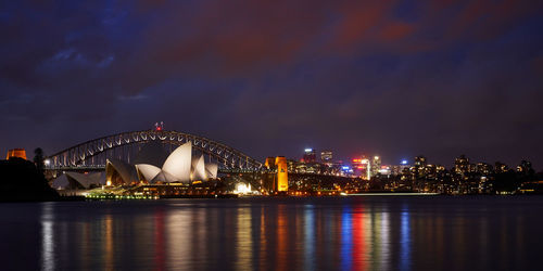 The sydney opera house and harbour bridge just after sunset with colourful reflections in the water 
