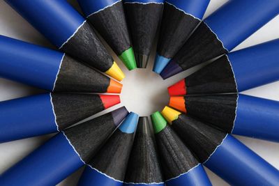 Directly above shot of colored pencils arranged in circular shape against white background