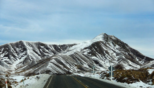 Road amidst snowcapped mountains against sky
