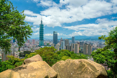 View of trees and buildings against cloudy sky