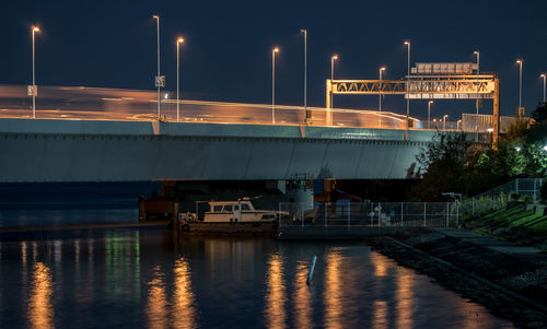 Illuminated bridge over river against sky in city at night