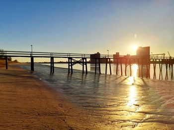 Pier over sea against clear sky during sunset