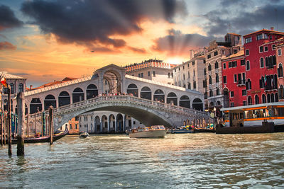 Bridge over canal in city against sky during sunset