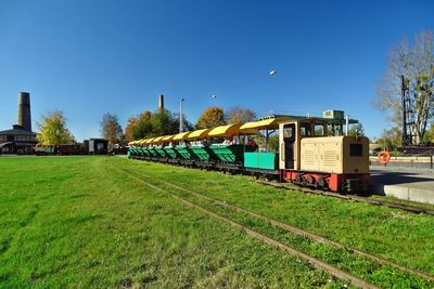 Train on grassy field against clear blue sky