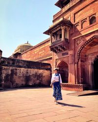 Full length of woman walking against historic building