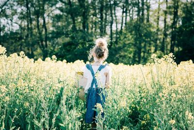 Young girl walking through a yellow flower field in a pretty dress