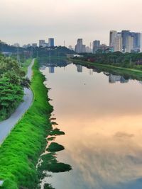 Scenic view of river by buildings against sky during sunset