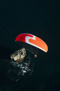 High angle view of red umbrella on rock by sea