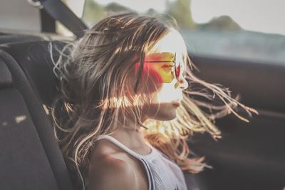 Close-up of thoughtful girl wearing sunglasses while traveling in car