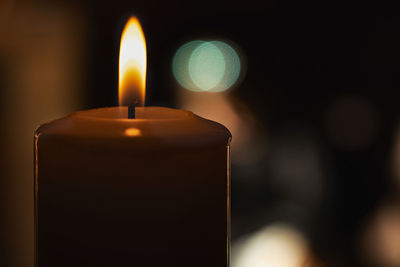Close-up of lit candle in darkroom