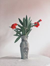 Close-up of red flower vase on table against wall