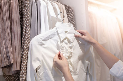 Female hand choosing clothes for checked pattern cotton polo shirt on the rack in cloth shop.