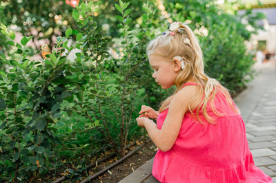 Side view of young woman standing against plants