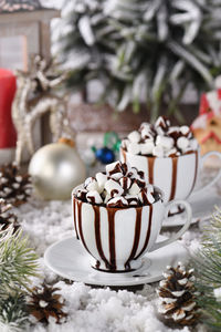 Hot chocolate with marshmallows in a white ceramic mug, with tangerines on a snowy table 