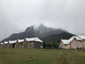 Built structure on field by mountains against sky