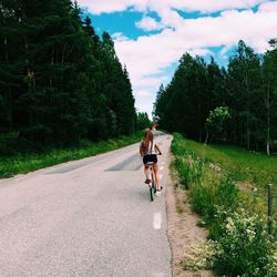 Rear view of woman riding bicycle on road