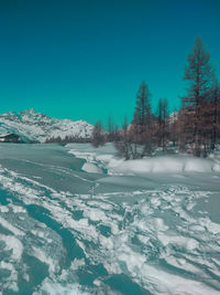 Snow covered landscape against clear blue sky