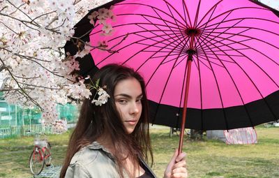 Portrait of beautiful woman with pink umbrella in rain