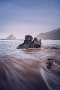 Rock formation on beach against sky