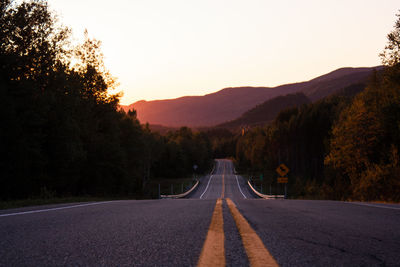 Road amidst trees with sunset