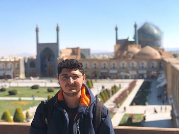 Portrait of young man standing against cityscape