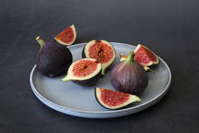 Round plate with sliced figs, small fork, whole fig and pieces, fruit with lots of small seeds