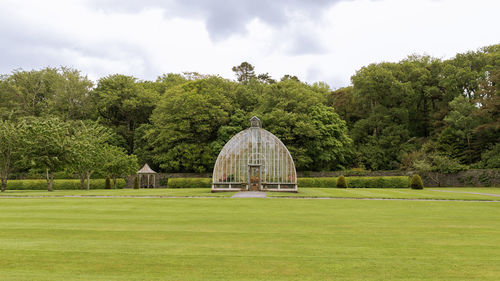 Trees on field against sky a greenhouse of glass in irland