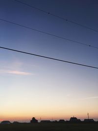 Electricity pylon against sky at sunset