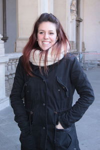 Smiling young woman wearing warm clothing in city during winter