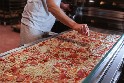 Midsection of man preparing large pizza