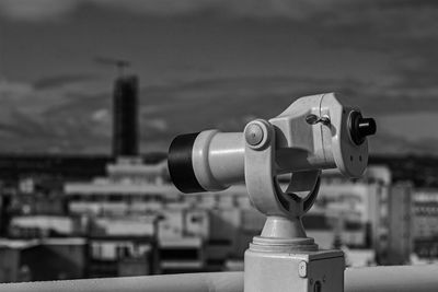 Close-up of coin-operated binoculars against cityscape