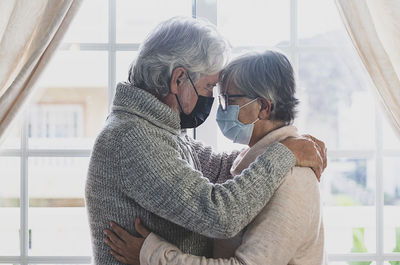 Rear view of couple kissing against blue sky