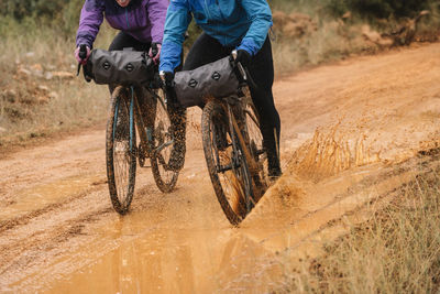 People in protective helmet and colorful jacket riding bikes in forest during bike packing adventure