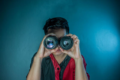 Portrait of man photographing against blue background