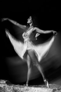 Midsection of woman dancing against black background